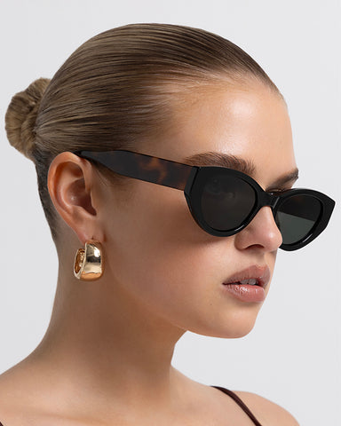 Women’s black cat-eye sunglasses with chunky acetate frame, tinted lenses, side view on model
