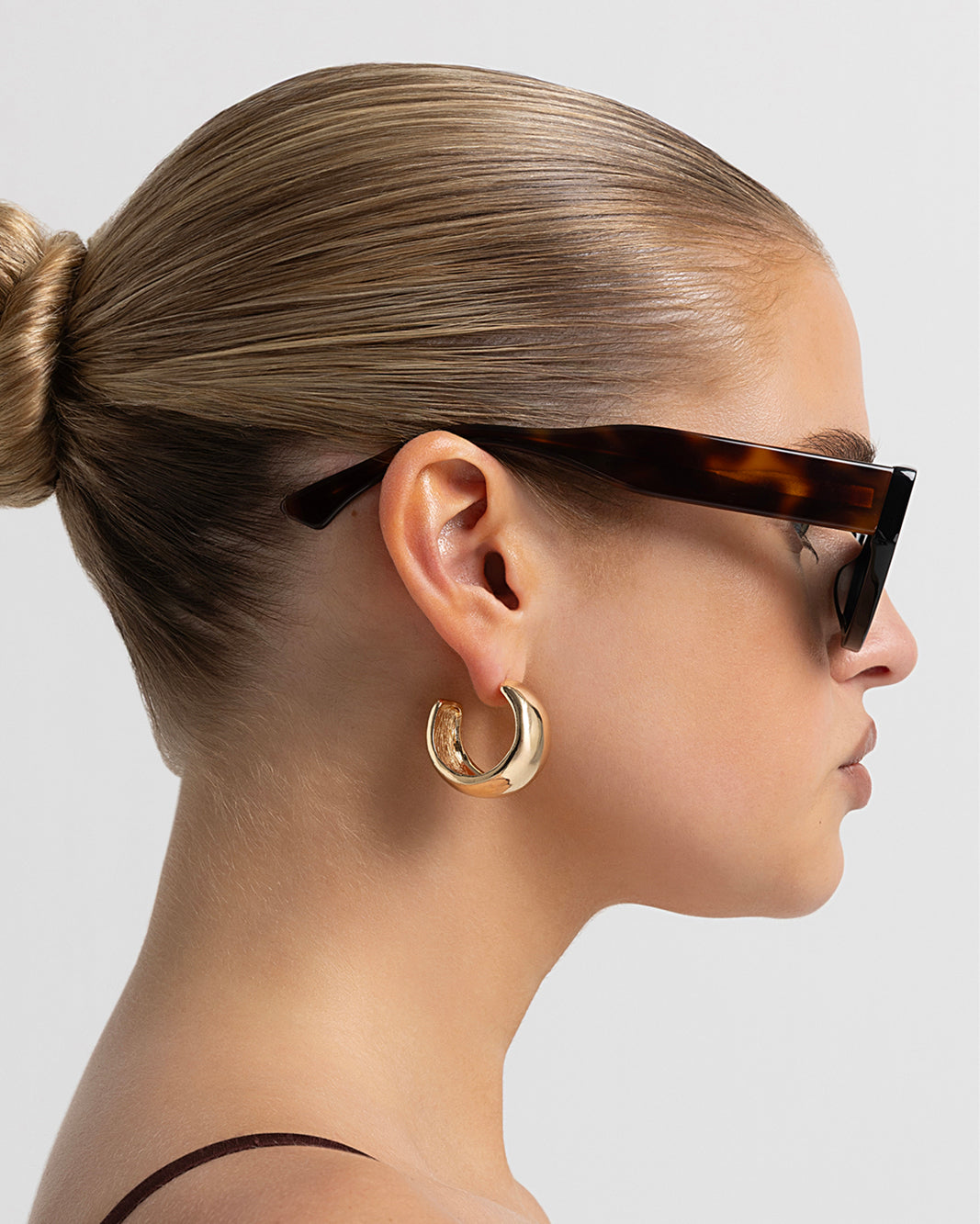 Women’s black cat-eye sunglasses with chunky acetate frame, tinted lenses, side view on model