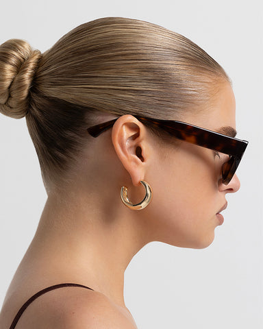 Women’s tortoiseshell cat-eye sunglasses with UV protection, chunky acetate frame, tinted lenses and wide temples, side view on model.