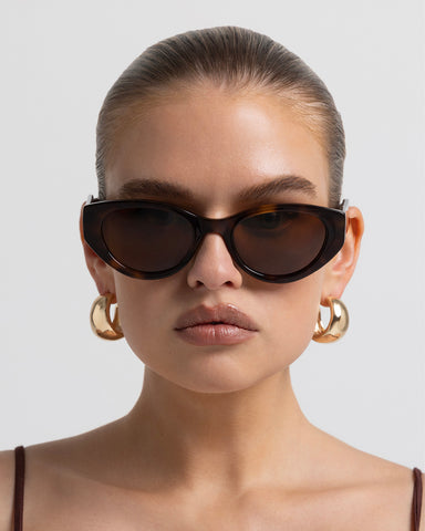 Women’s tortoiseshell cat-eye sunglasses with UV protection, chunky acetate frame, tinted lenses and wide temples, front view on model.