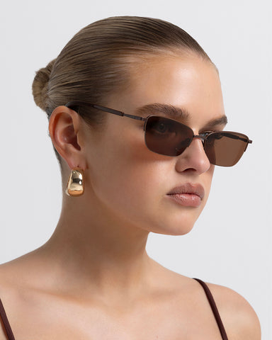 Women’s metal cat-eye sunglasses with UV protection, thin frame, brown tinted lenses, side view on model
