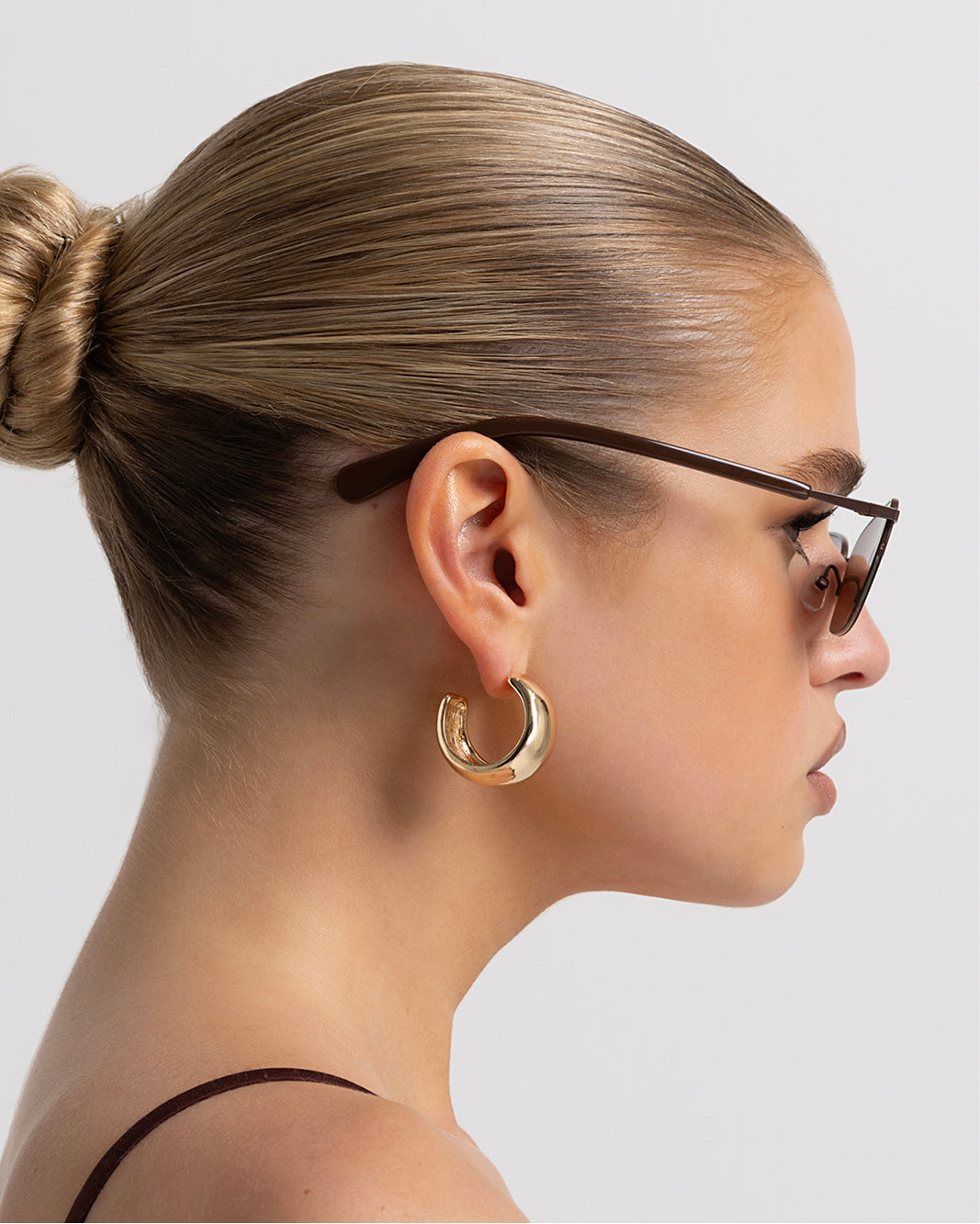 Women’s metal cat-eye sunglasses with UV protection, thin frame, brown tinted lenses, side view on model