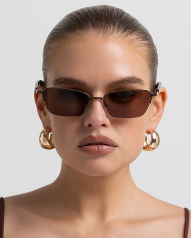 Women’s metal cat-eye sunglasses with UV protection, thin frame, brown tinted lenses, front view on model