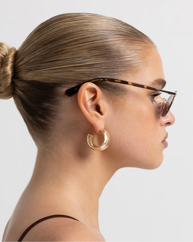 Women’s gold-tone metal and tortoiseshell accents, cat-eye sunglasses with rectangular tinted lenses, thin frame, side view on model