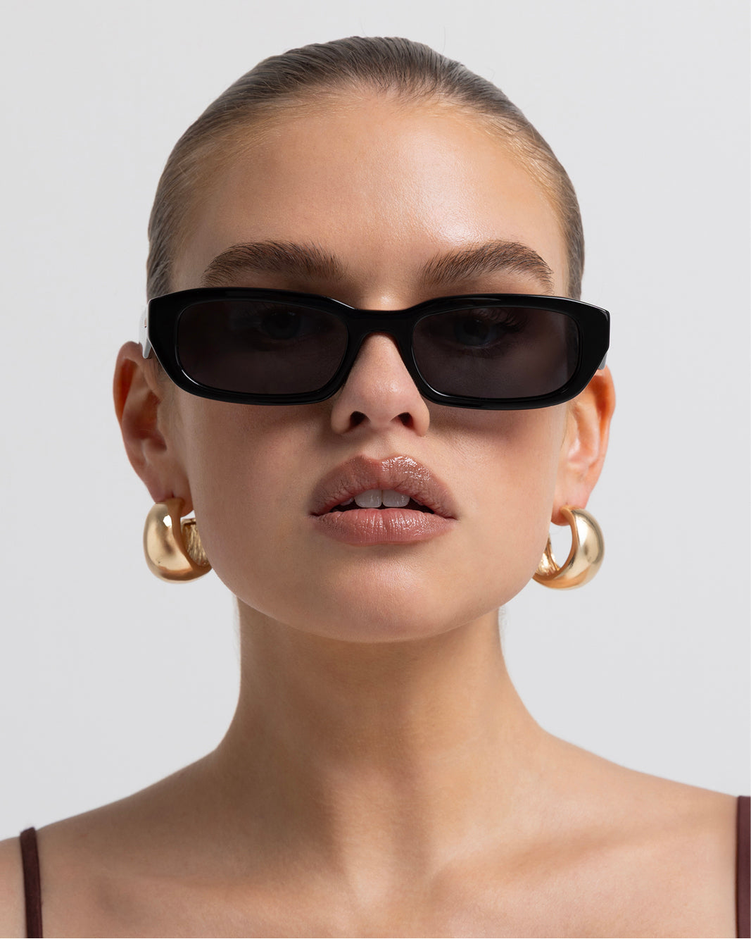 Women's sunglasses with a rectangular silhouette, chunky acetate frame, tonal tinted lenses, and wide arms for a bold, modern look with UV protection, front view.
