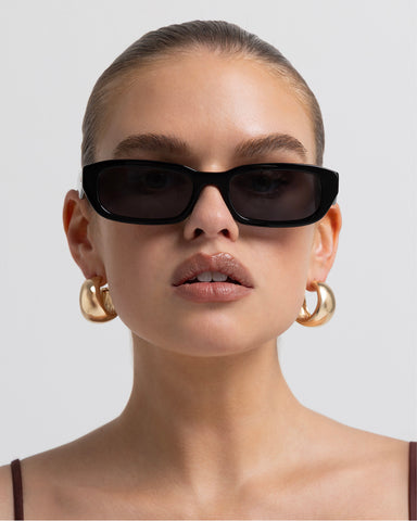 Women's sunglasses with a rectangular silhouette, chunky acetate frame, tonal tinted lenses, and wide arms for a bold, modern look with UV protection, front view.
